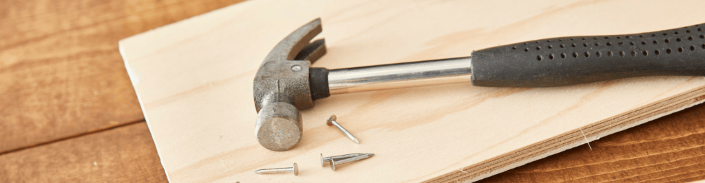 Ein Hammer und Nägel auf einem Holzbrett