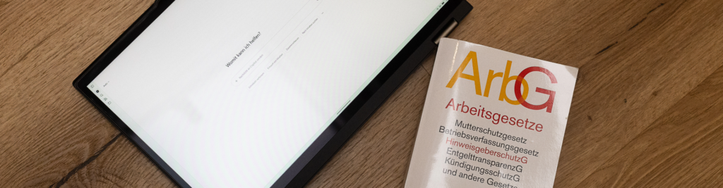 Auf einem Tablet ist Microsoft Copilot geöffnet und daneben liegt ein Arbeitsgesetzbuch