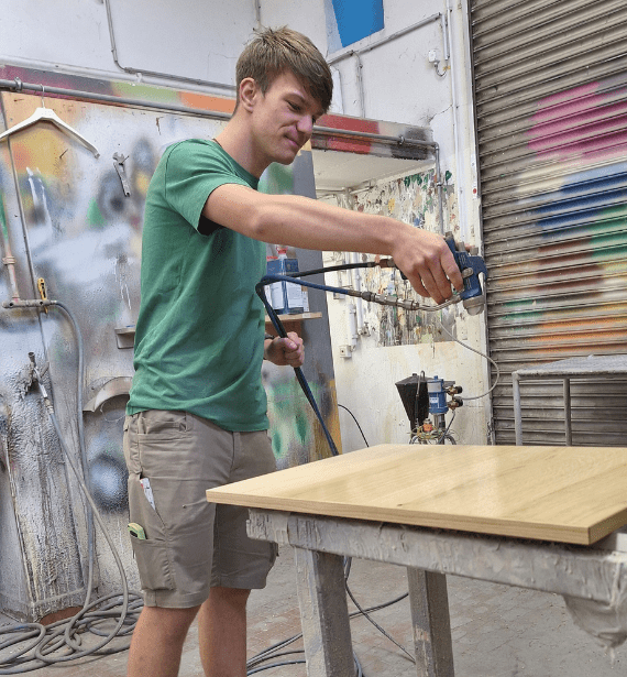 Azubi Pit lakiert das Holz für das neue Projket