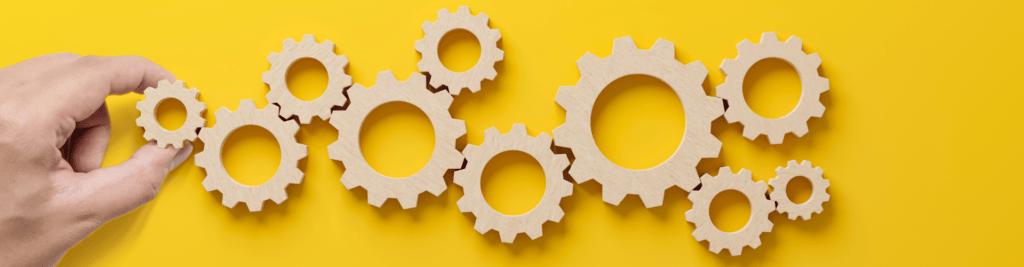 Eine Hand setzt verschiedene Zahnräder aneinander