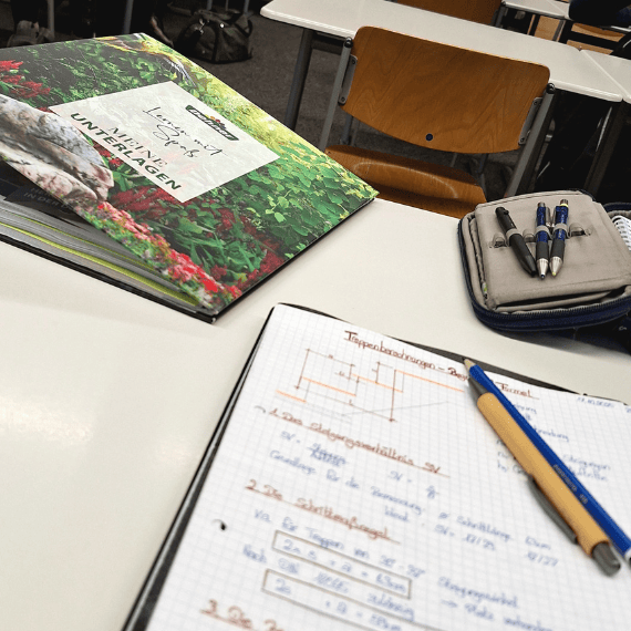 Schulmaterialien wie Block, Stifte und Ordner auf einem Tisch