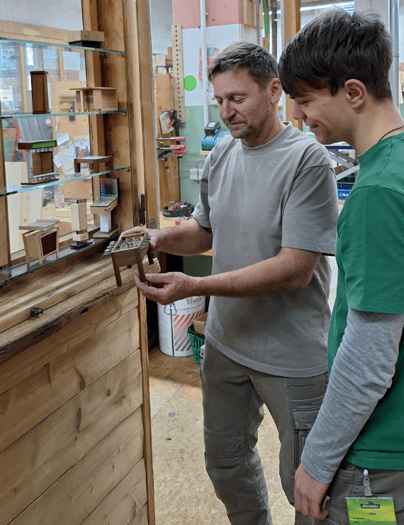 Ein Ausbilder zeigt einem Azubi ein Werkstück in der Schreinerei