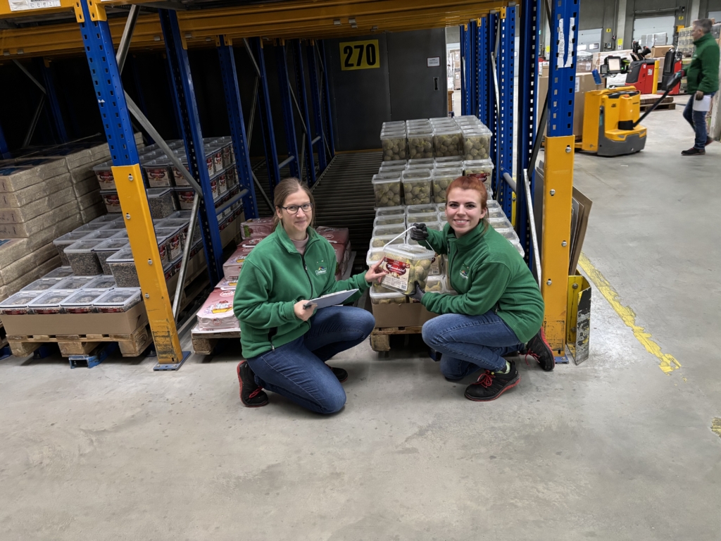 Zwei Frauen in grünen Westen sitzen im Lager