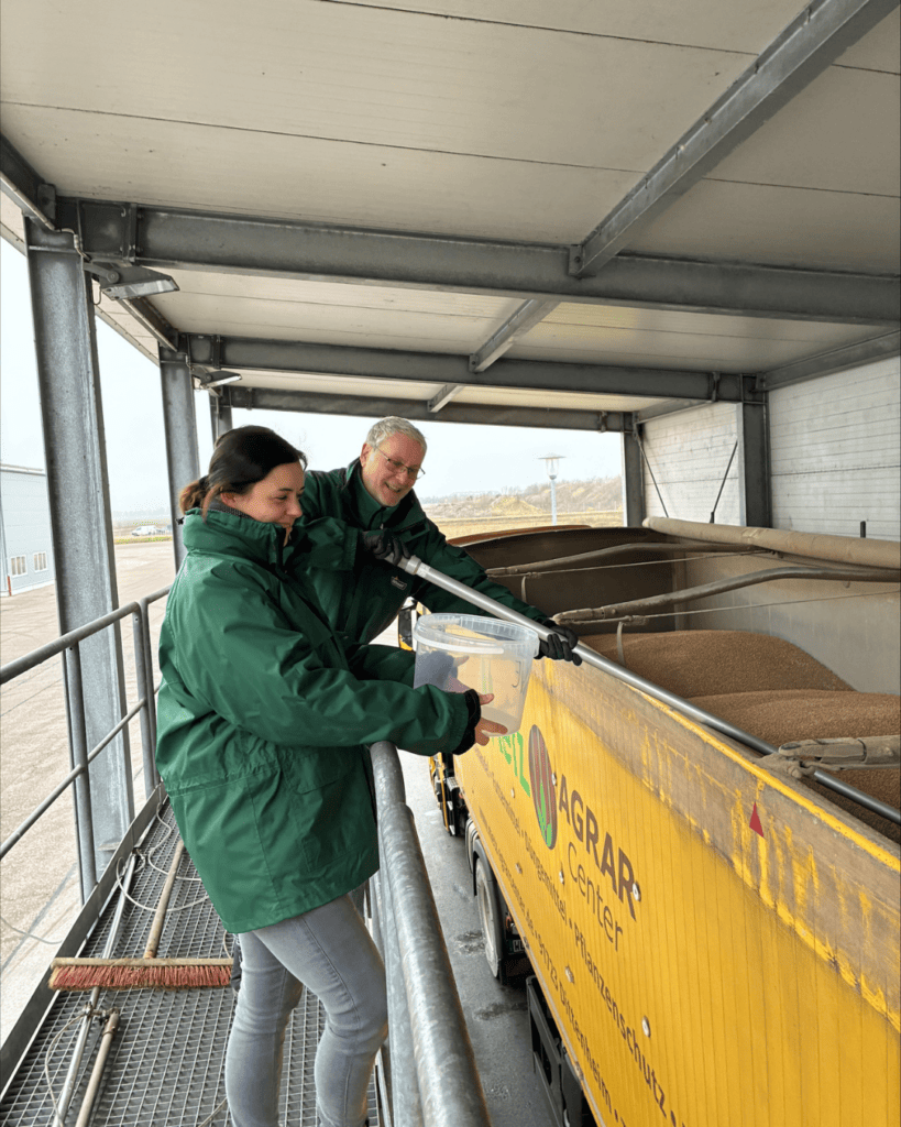 Eine Frau und ein Mann stehen vor einer LKW Ladung und begutachten die Ware