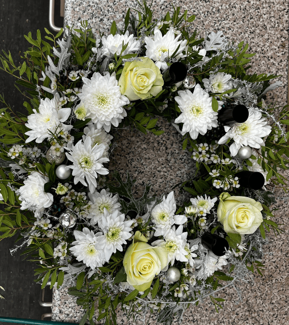 winterlicher Kranz mit weißen Blüten und verschiedenen Zweigen