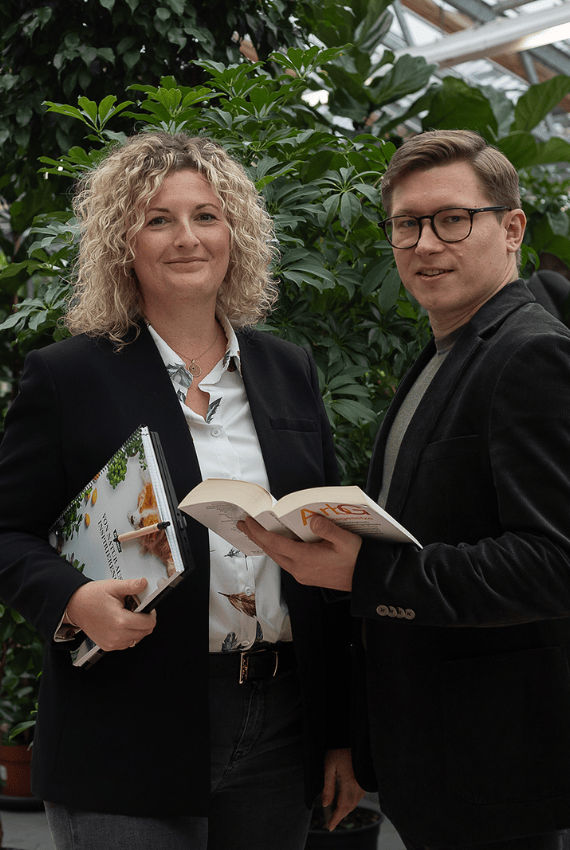 Ein Mann und eine Frau stehen im Business-Outfit arbeiten zusammen