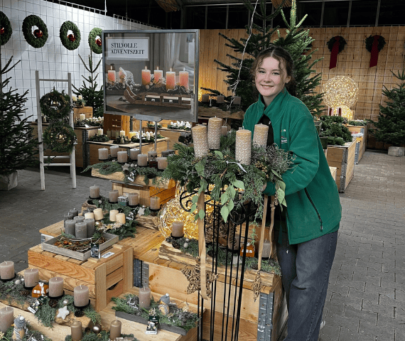 Junge Frau präsentiert Adventskranz in Naturtönen