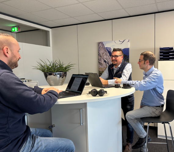 Drei Männer sitzen an einem Tisch und führen eine Besprechung