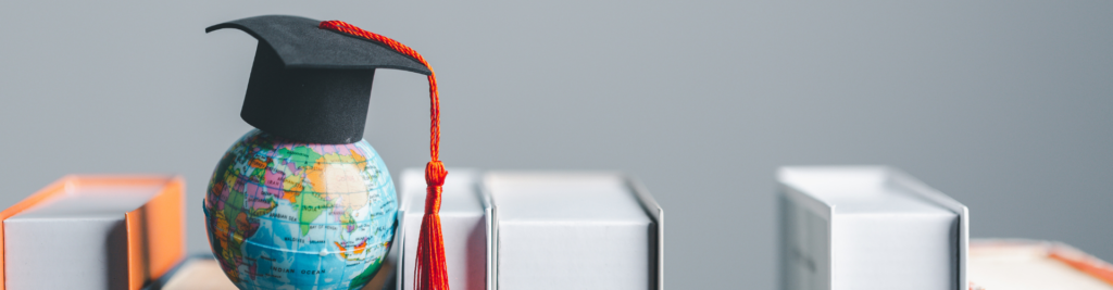 Kleine Weltkugel mit einem Absolventenhut in einem Bücherregal