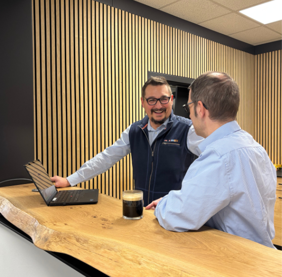 Zwei Männer stehen in einer Kaffeeküchen und unterhalten sich