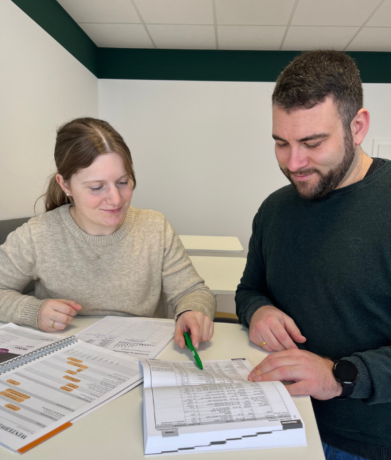 Eine Frau und ein Mann stehen an einem Tisch und prüfen ein Dokument