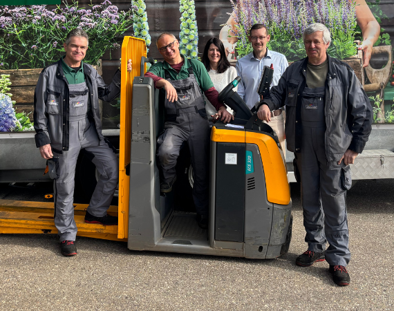 Fünf Menschen und ein Flurförderzeug stehen vor einem Anhänger mit Dehner Logo