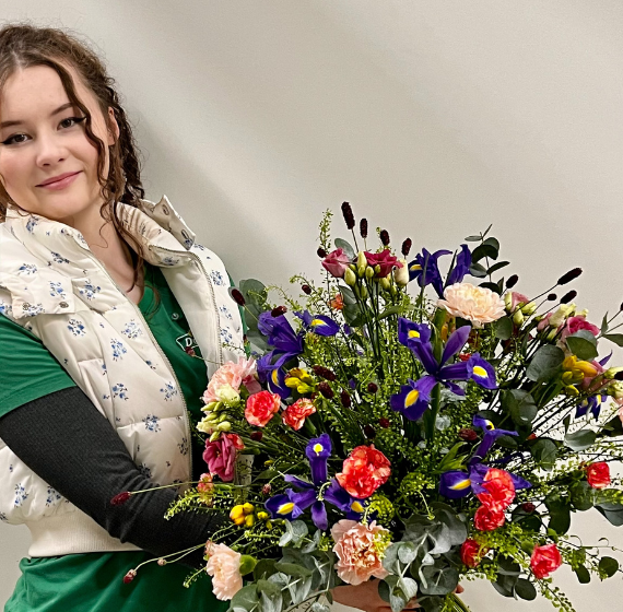Auszubildende hält einen üppigen Blumenstrauß in den Händen