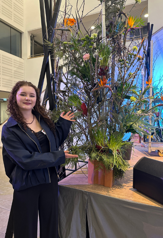 Auszubildende präsentiert ein großes Blumenarrangement