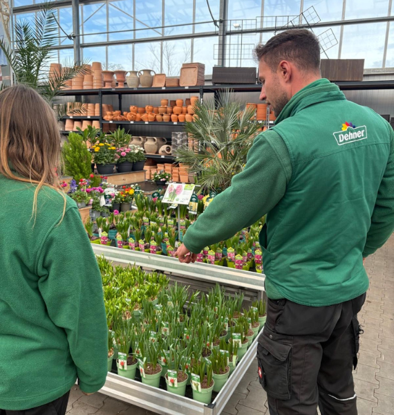 Ein Mann in grüner Jacke erklärt einer Mitarbeiterin, wie die Pflanzen präsentiert werden müssen