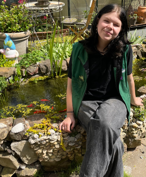 Junge Frau sitzend an einem Teich