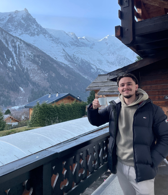 Junger Mann mit Kaffee-Tasse in den Bergen