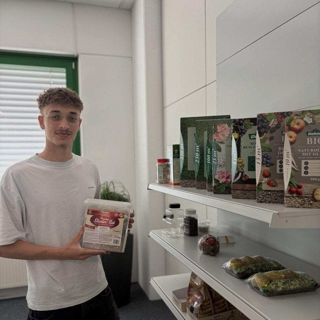 junger Mann mit einer Box mit Dünger in der Hand