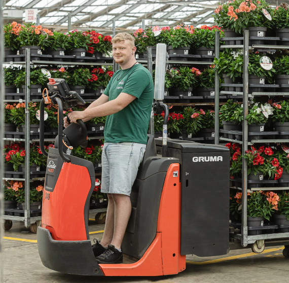 Auszubildender transportiert Blumen auf einem Flurförderfahrzeug