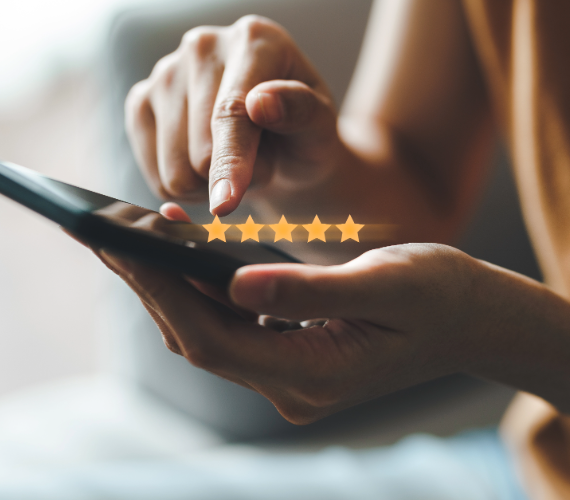 Eine Person hält ein Smartphone in der Hand, tippt mit dem Finger auf dem Display und gibt eine Bewertung ab