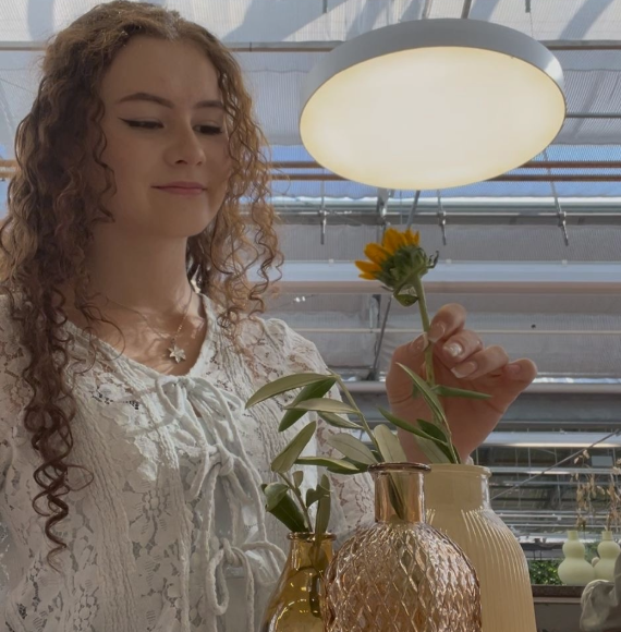 Junge Frau arrangiert Blumen in eine Vase