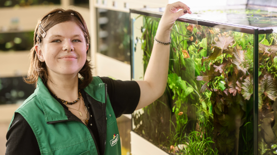 Junge Frau füttert Fische im Aquarium