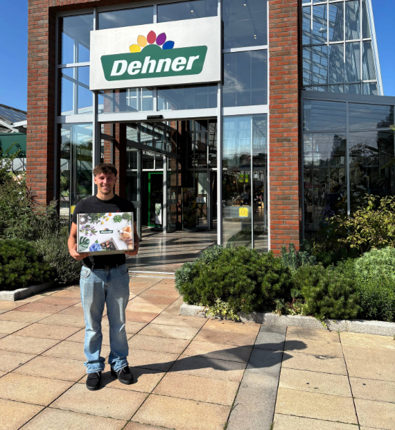 Auszubildender mit einer Onboarding-Box vor dem Garten-Center